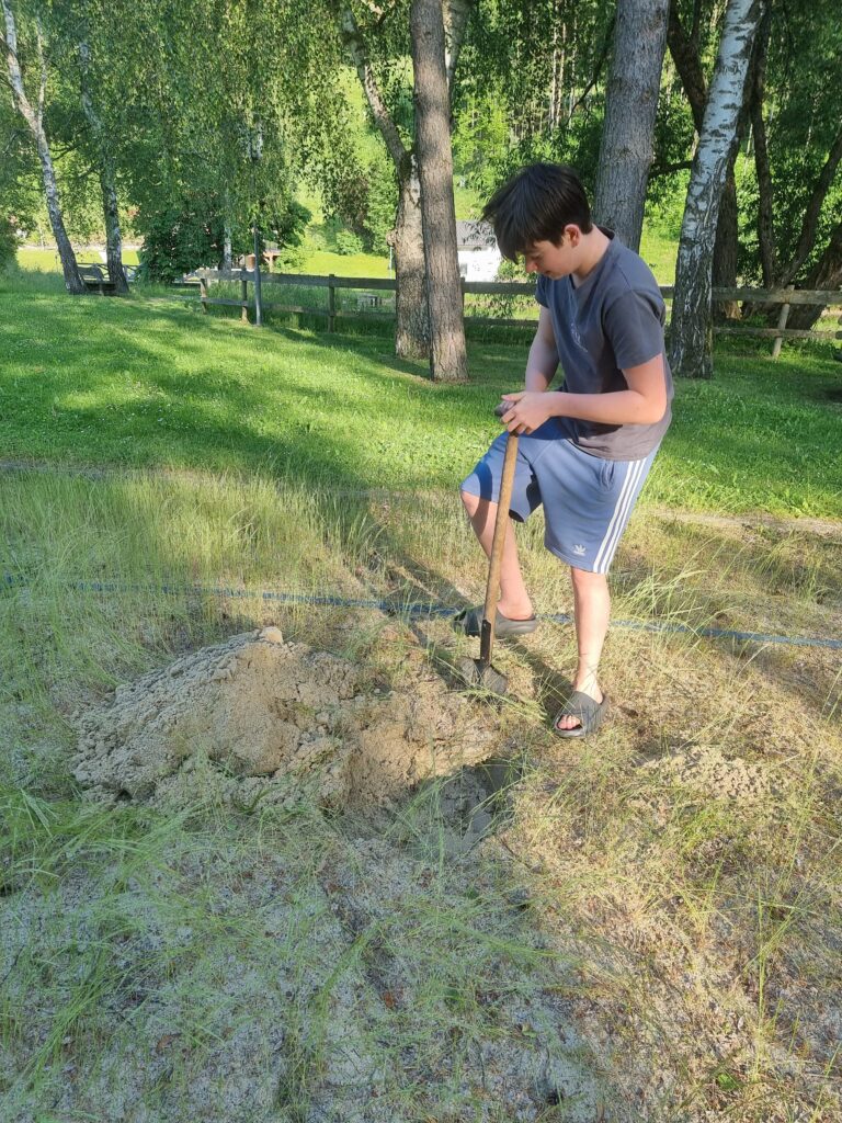 Schaufeln am verwahrlosten und mit Unkraut überwucherten Beachplatz vor der Reinigung